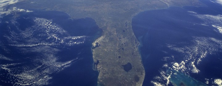 Taken during the STS-95 mission from a point over Cuba, this photo shows an oblique, foreshortened view of the Florida Peninsula, with the light blue, shallow seafloor of both the Florida Keys (curving across the bottom of the view) and the Bahama banks (right). "Popcorn" cumulus cloud covers Miami and the Southern Everglades, although the built-up area from Ft. Lauderdale to West Palm Beach can be discerned. Lake Okeechobee is the prominent waterbody in Florida. Cape Canaveral is shown well, half way up the peninsula. Orlando appears as the lighter patch West (left) of Cape Canaveral, near the middle of the peninsula. Cape Hatteras appears top right, with the North part of Chesapeake Bay also visible. This is a visibility of 16 degrees of latitude (23 degrees N over Cuba to 39 degrees at Baltimore), showing unusual atmospheric clarity.
Credit: NASA
